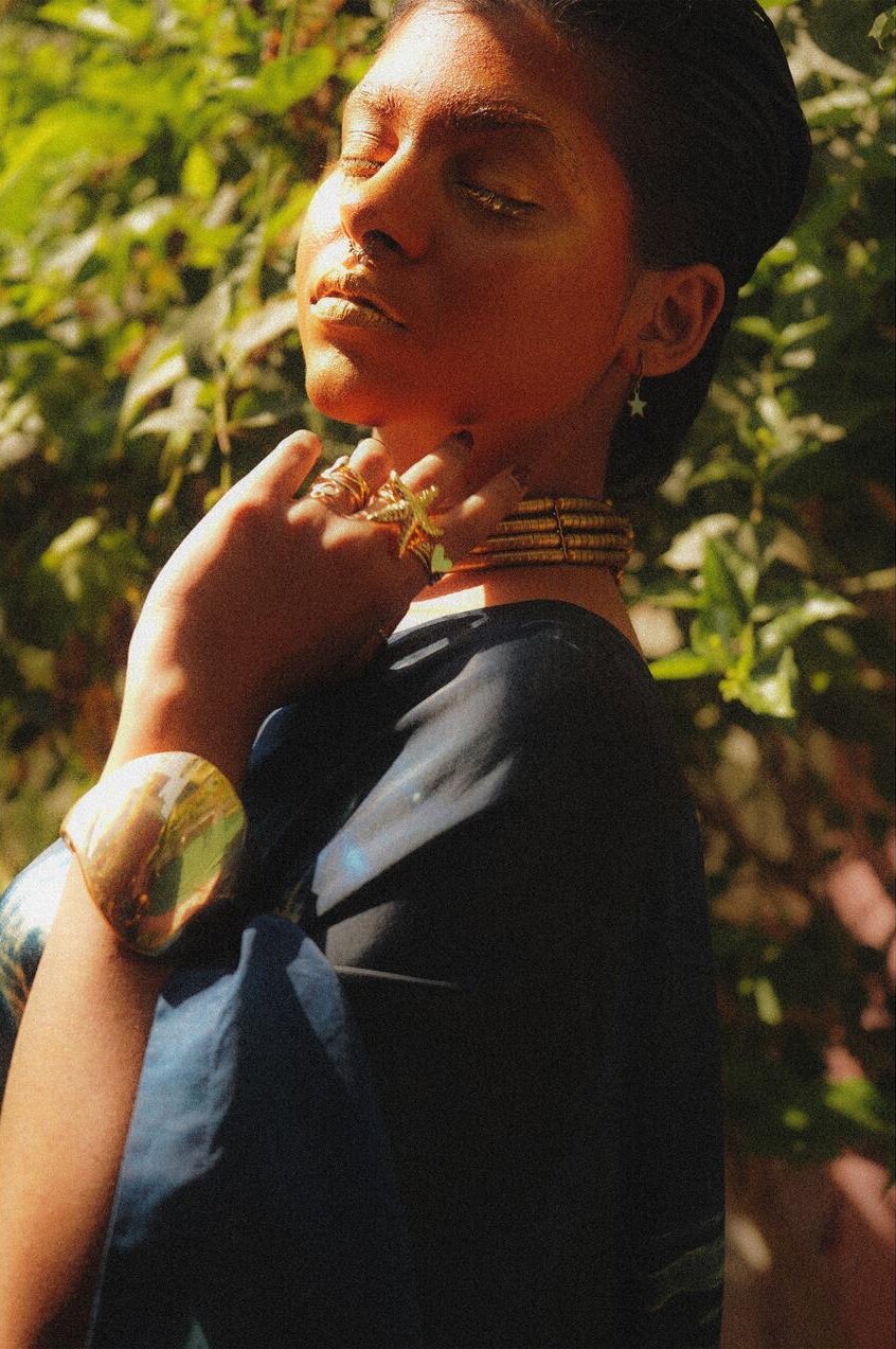 Model in golden light with gold rings and choker