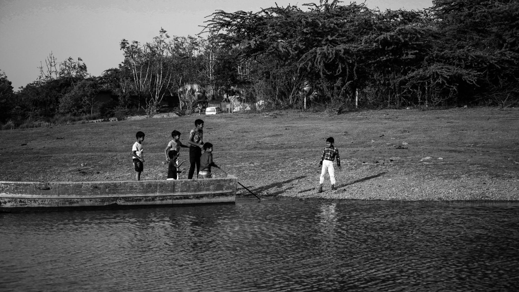 Kids playing on a boat at the riverbank, black and white